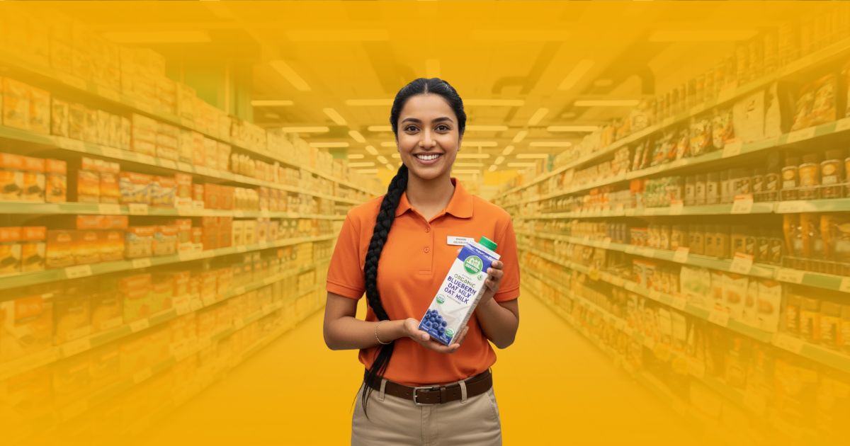 Promotor de café de Poder Comercial sonriendo y gesticulando en un stand de degustación de café en un supermercado.